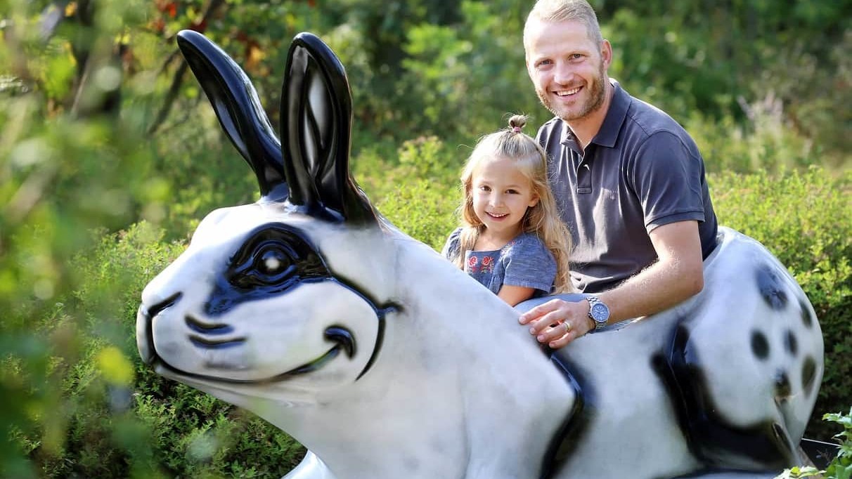 Ein Mann sitzt mit einem Mädchen in einem weißen Kaninchen der Moggelesbahn.