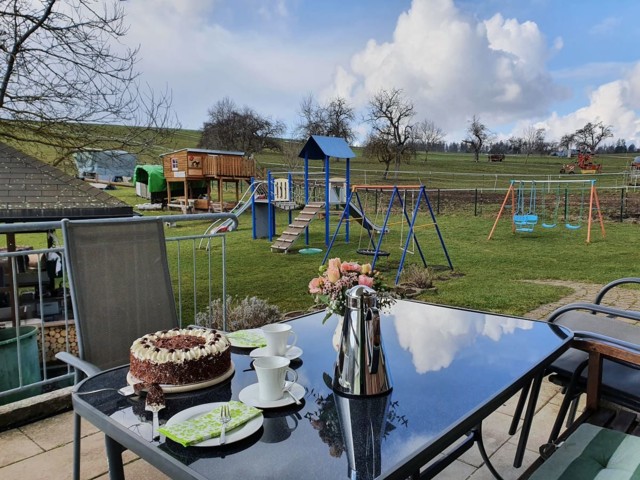 Kaffee & Schwarzwälder Kirschtorte mit Blick auf den Spielplatz und die Wiesen um den Ferienhof