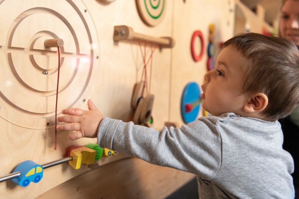 Ein Kleinkind spielt an einem Holzspielzeug in der Spielscheune Unterkirnach.