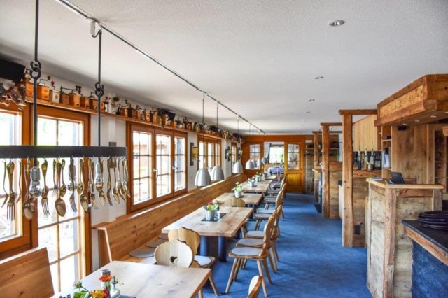 Der traditionelle und moderne Gastraum mit Holzmöbeln, blauem Teppichboden und altem Besteck als orginelle Dekoration lädt zum Verweilen ein.