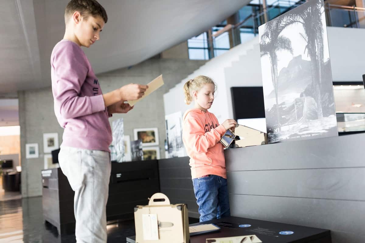 Zwei Kinder schauen in ihren Museumkoffer aus Karton. Mit dem Koffer können sie das Zeppelin Museum auf eigene Faust entdecken.