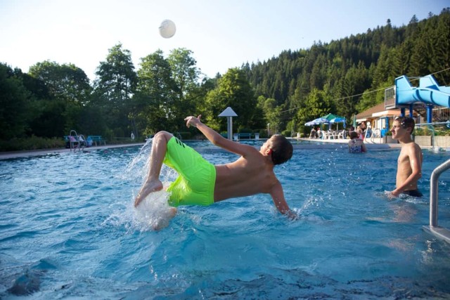 Zwei Teenager spielen mit einem Ball im Freibad Schönmünzach.