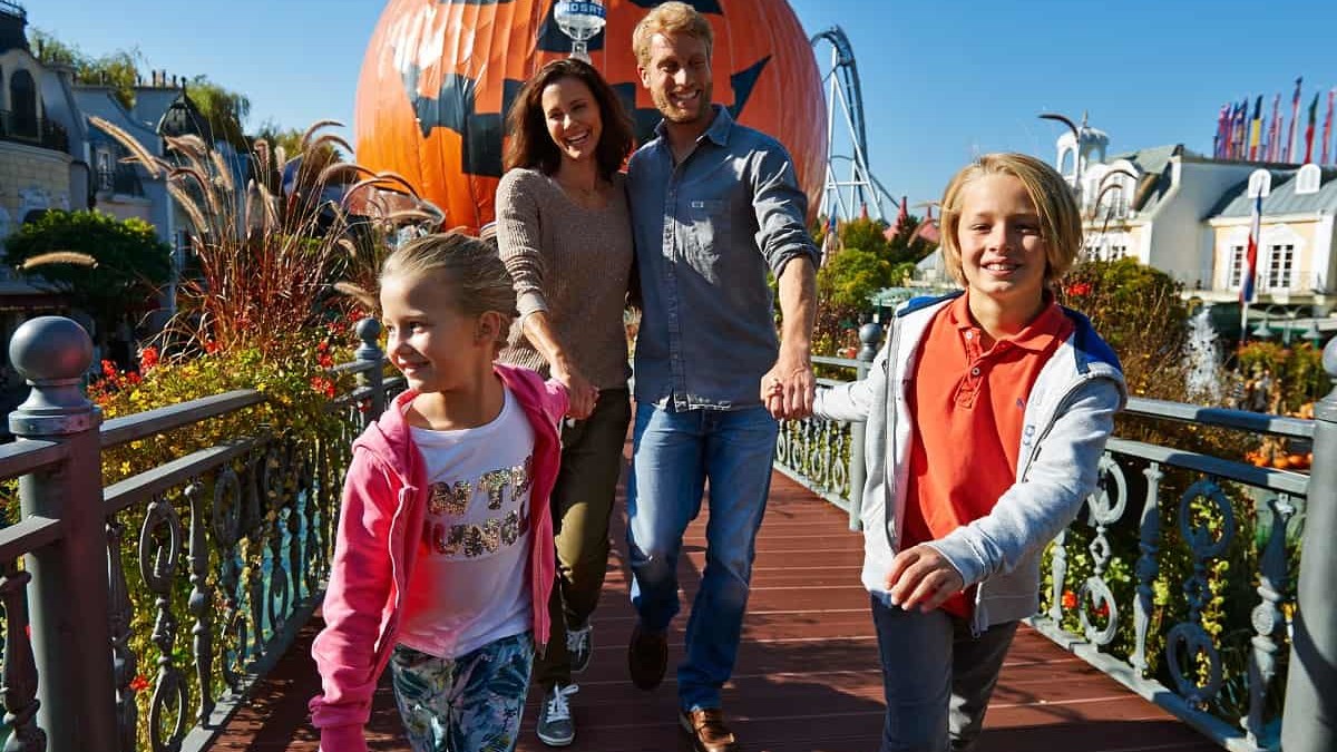 Freizeitparkbesuch im Herbst: Eine Familie ist im Französischen Themenbereich unterwegs, im Hintergrund steht der Eurosat CanCan Coaster als Riesenkürbis verhüllt.