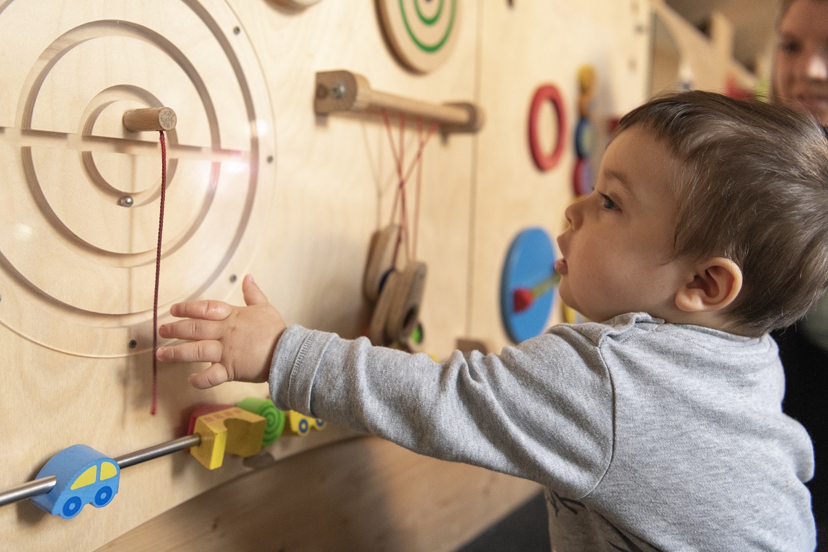 Ein Kleinkind spielt an einem Holzspielzeug in der Spielscheune Unterkirnach.